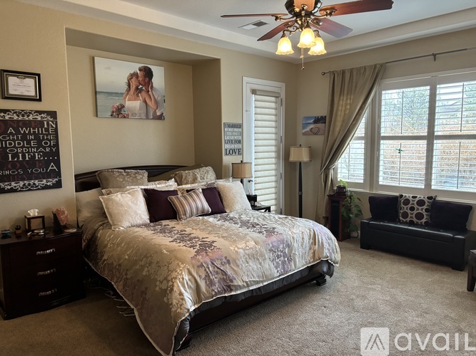 A bedroom with a large bed and a ceiling fan.