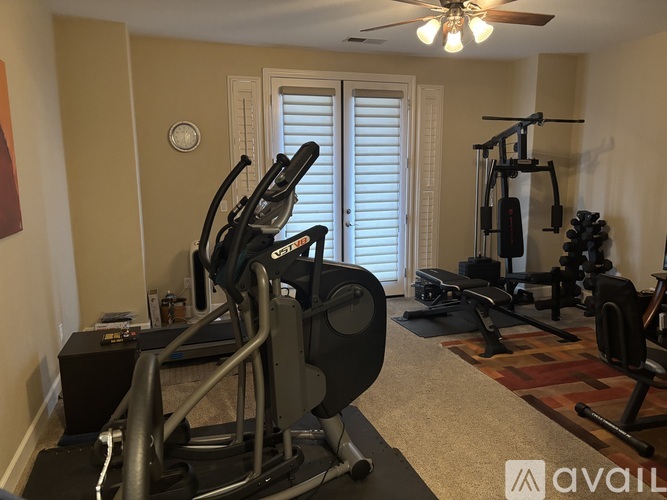 A home gym with a treadmill, elliptical trainer, and other exercise equipment.