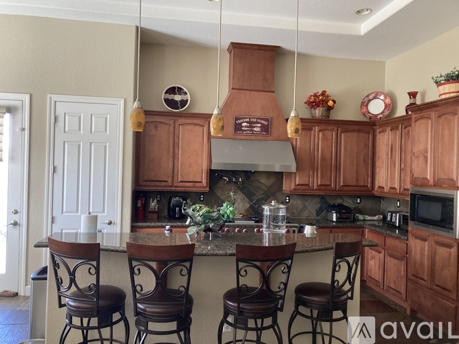A kitchen with wooden cabinets and a center island with chairs.