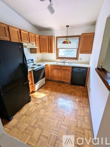 A kitchen with wooden cabinets and a black fridge.