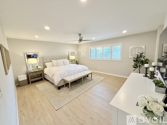 A bedroom with a large bed, a TV, and a ceiling fan.