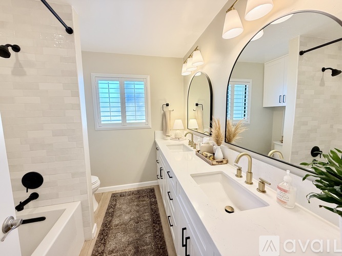 A bathroom with a white tub, sink, and mirror.