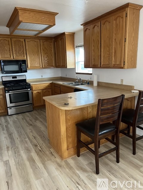 A kitchen with wooden cabinets and a wooden island with two chairs.