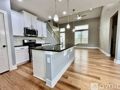 A kitchen with white cabinets and a wooden floor.