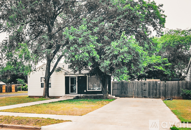 A house with a white fence and a tree in front.