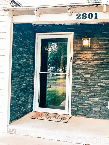 A door with a glass window and a brick wall.