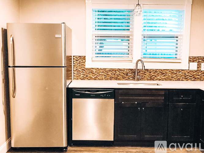 A kitchen with a stainless steel refrigerator, dishwasher, and black cabinets.