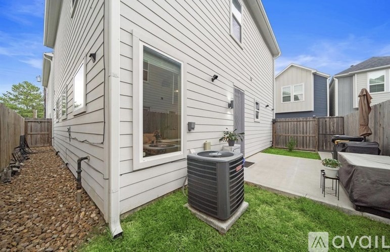 A house with a grey siding and a window with a fan on the balcony.