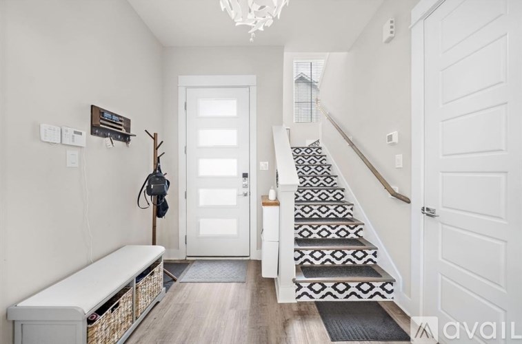 A hallway with a bench, a coat rack, and a staircase.