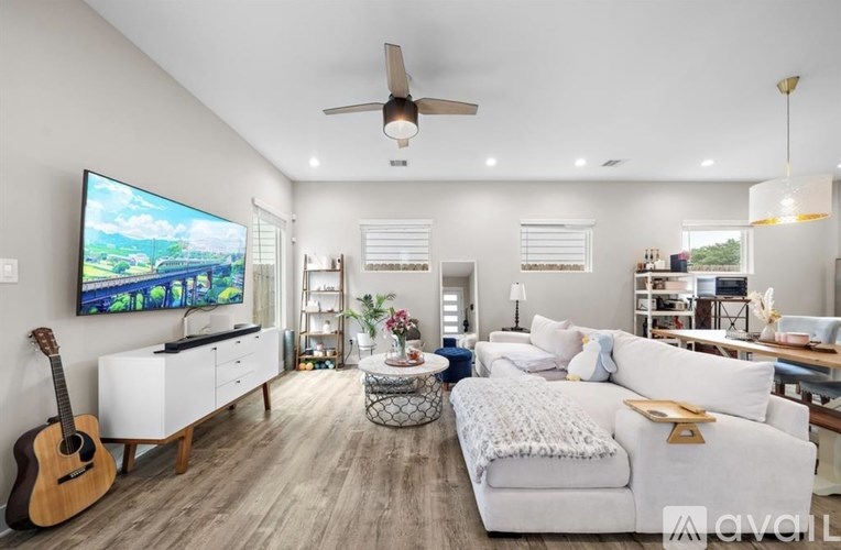A modern living room with a large TV, a white sofa, and a guitar on the floor.