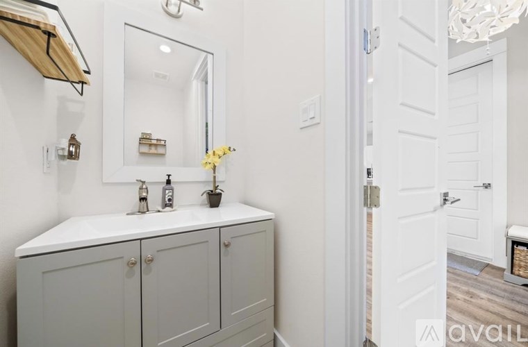 A bathroom with a white cabinet and a mirror above it.