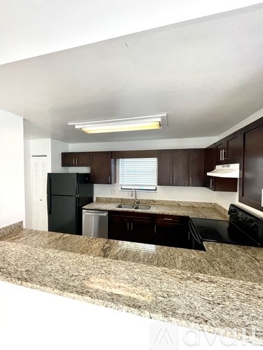 A kitchen with granite countertops and dark brown cabinets.
