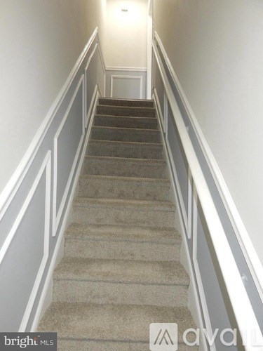 A staircase with a carpeted runner and white walls.
