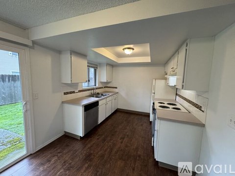 A kitchen with white appliances and wooden floors.