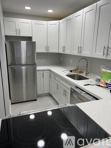 A kitchen with white cabinets and a stainless steel refrigerator.