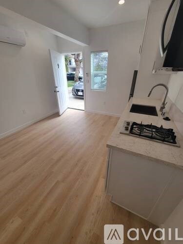 A kitchen with a stove top oven and wooden flooring.