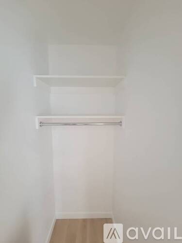 A white wall with two shelves and a wooden floor.