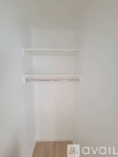 A white wall with two shelves and a wooden floor.