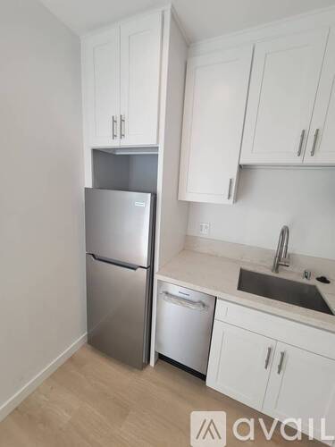 A kitchen with white cabinets and a stainless steel refrigerator.