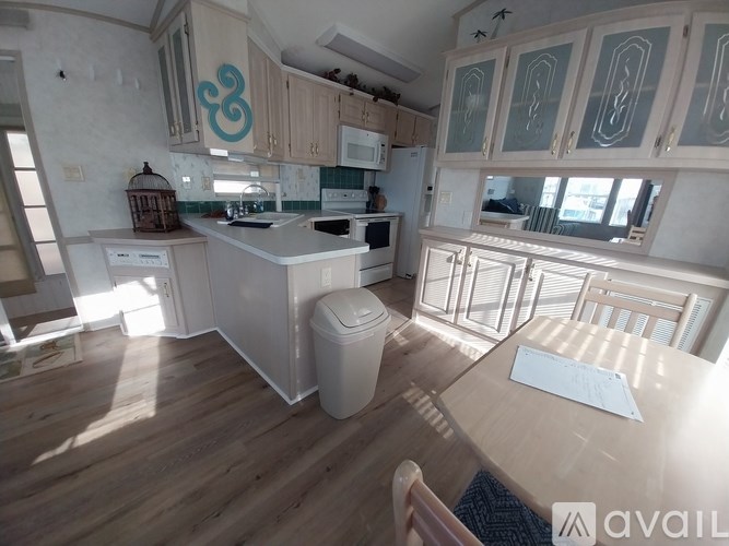 A kitchen with wooden floors and a table in the middle.