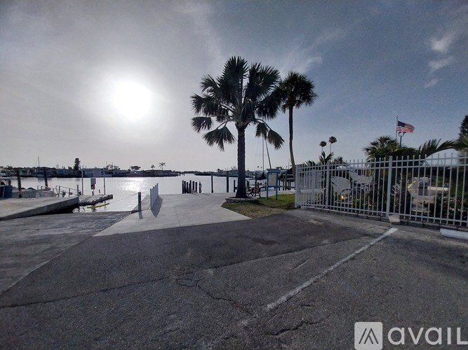 A sunny day at the beach with palm trees and a fence.