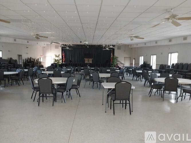 A large room with tables and chairs and a stage at the back.