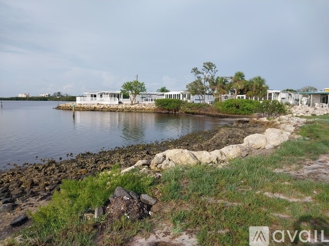 A body of water with a rocky shore and a white building in the distance.