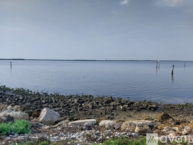 A rocky shoreline with a body of water and a cloudy sky.