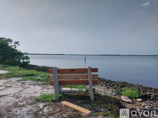 A wooden bench sits on a rocky shore by the water.