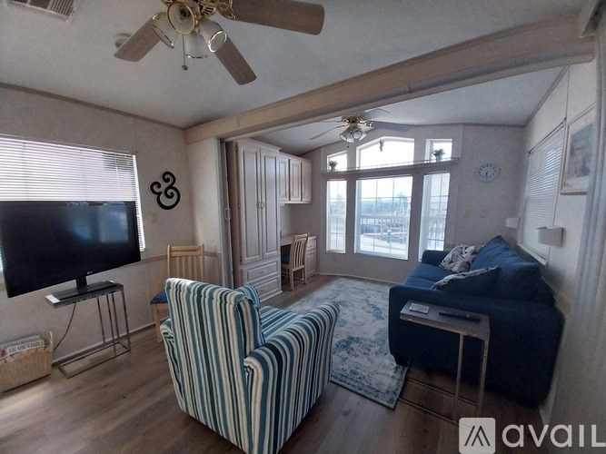 A living room with a striped chair and a flat screen TV.