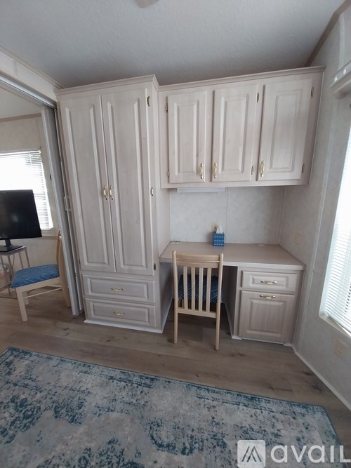 A room with a desk and a chair in front of a cabinet.