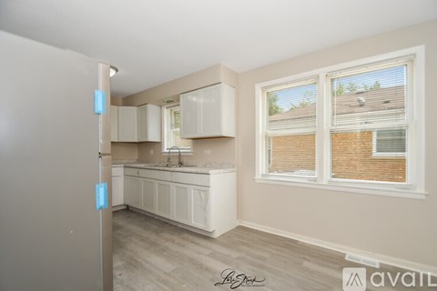A kitchen with white cabinets and a window with blinds.
