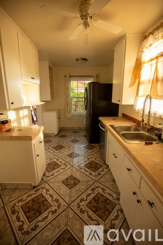 A kitchen with a tiled floor and a ceiling fan.