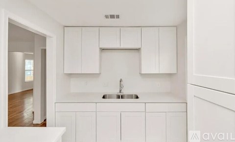 A white kitchen with a sink and cabinets.