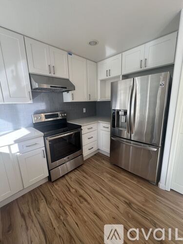 A kitchen with white cabinets and a stainless steel refrigerator.