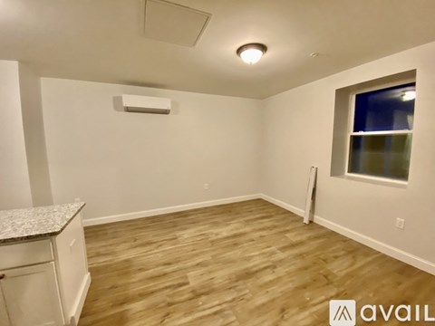 A room with wooden flooring and a window with a view of a building outside.