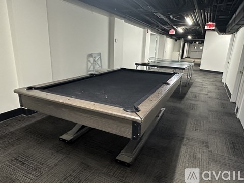 A pool table in a room with carpeted flooring and white walls.