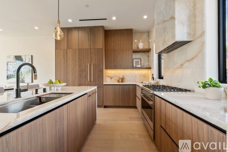 A modern kitchen with wooden cabinets and a marble countertop.