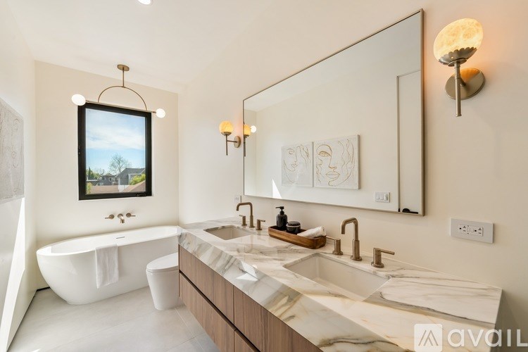A bathroom with a tub, sink, mirror, and a window.