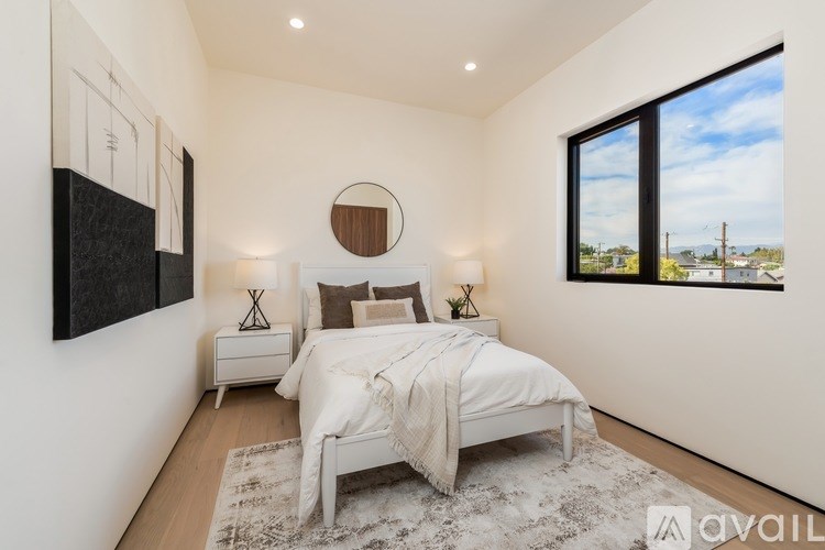 A bedroom with a large bed, a round mirror, and a painting on the wall.
