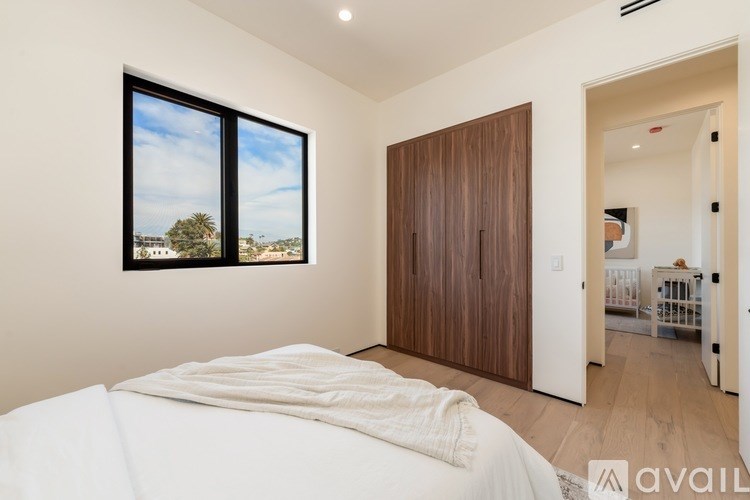 A bedroom with a large bed and a view of the outside through a window.