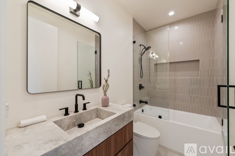 A modern bathroom with a marble countertop and a large mirror above the sink.