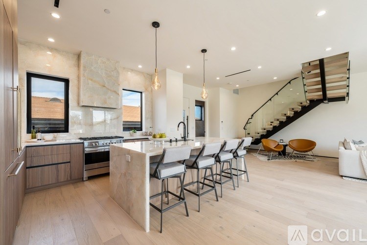 A modern kitchen with a wooden island and a staircase in the background.