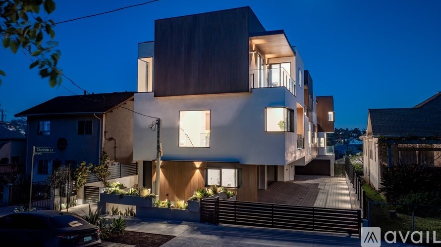 A modern house with a wooden exterior and large windows is illuminated at night.