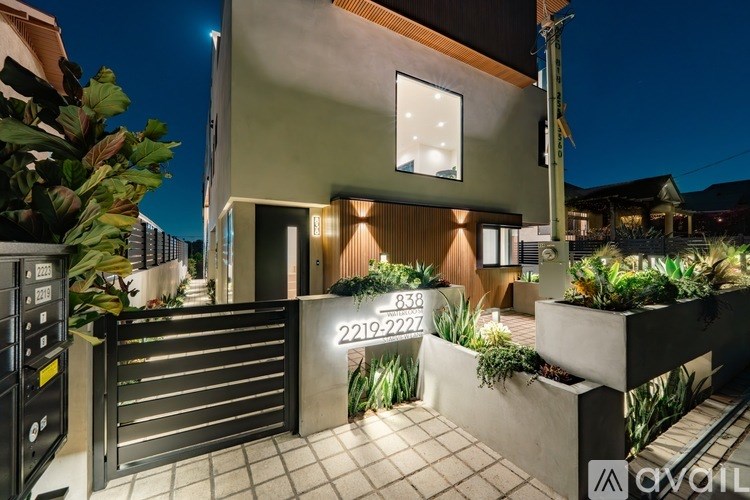 A modern house with a black gate and a lit up sign that reads "AVAILABLE".