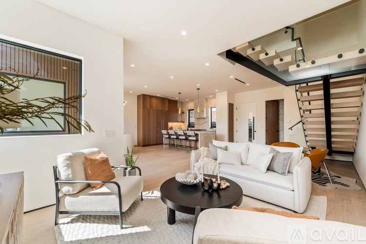 A modern living room with white furniture and a spiral staircase.