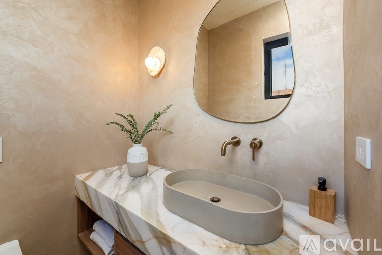 A bathroom with a round mirror and a marble countertop.