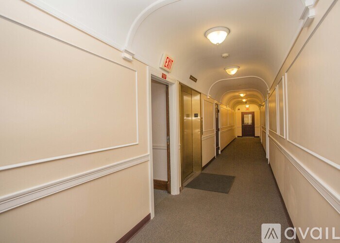 A long hallway with a red exit sign on the wall.