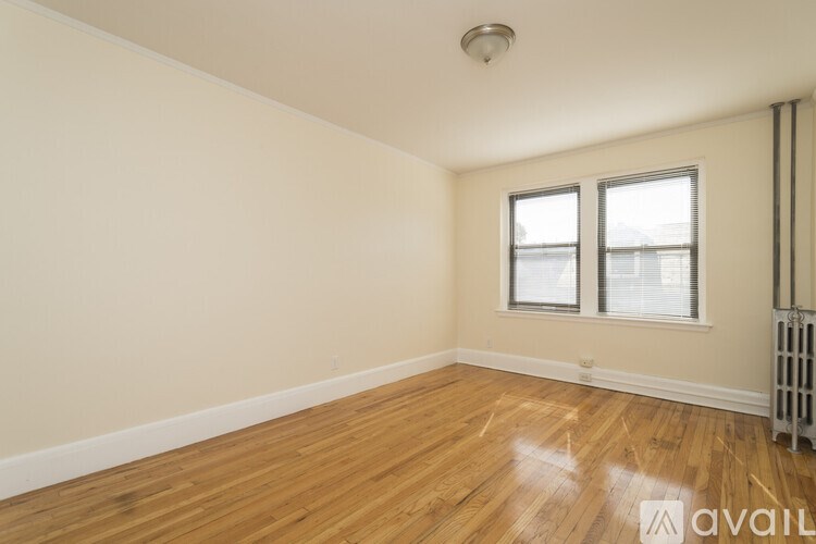 A room with wooden floors and a window with blinds.