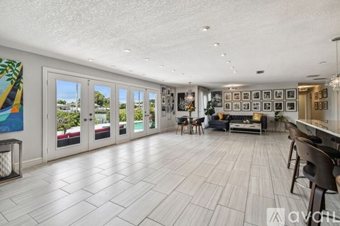A spacious living room with a large painting on the wall and a view of the backyard through the sliding glass doors.